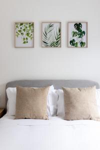 een slaapkamer met een wit bed met vier foto's aan de muur bij Flatzy - Stunning Home by Lark Lane with Pool Table in Liverpool