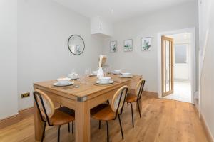 een eetkamer met een houten tafel en stoelen bij Flatzy - Stunning Home by Lark Lane with Pool Table in Liverpool