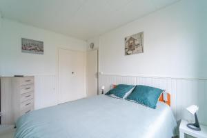 - une chambre blanche avec un lit et des oreillers bleus dans l'établissement Florévasion - Appt pour 5, à Bobigny