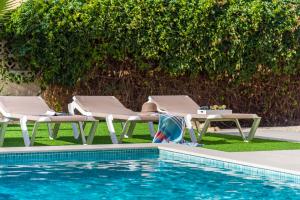 uma piscina com duas espreguiçadeiras e uma mesa ao lado de uma piscina em Villa Mila 10 - PlusHolidays em Calpe