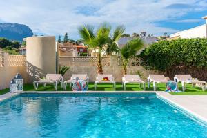 uma piscina com espreguiçadeiras e cadeiras em redor em Villa Mila 10 - PlusHolidays em Calpe