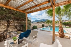 un patio esterno con tavolo, sedie e piscina di Villa Mila 10 - PlusHolidays a Calpe