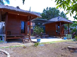a wooden cabin with a table and chairs in front of it at Yellow Coco Gili Gede in Gili Gede