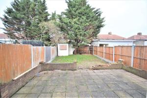 a backyard with a fence and a yard with trees at Lovely 3 Bedroom House Dagenham in Dagenham