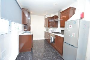 a kitchen with brown cabinets and a white refrigerator at Lovely 3 Bedroom House Dagenham in Dagenham