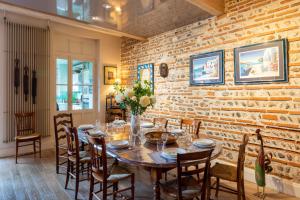 una sala da pranzo con tavolo, sedie e muro di mattoni di Le Clos Lamouroux - Grande maison pour 12 a Agen