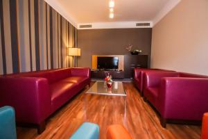 a living room with two red couches and a tv at IMPIQ Hotel in Trnava