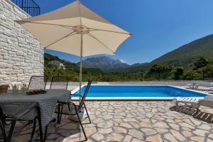 una mesa con sombrilla junto a la piscina en Charming holiday home Dolac in rural area with pool, en Slime