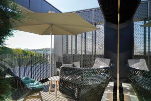 d'une terrasse avec des chaises et un parasol sur le balcon. dans l'établissement Rise - Penthouse Suite with Terrace, à Luxembourg