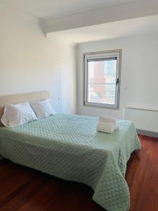 um quarto com uma cama com um edredão verde e uma janela em Expo Luxury apartment em Lisboa