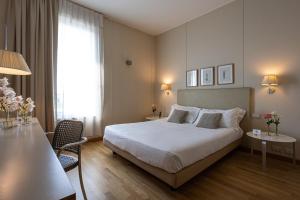 チニゼッロ・バルサモにあるコスモ ホテル パレスのベッド、テーブル、椅子が備わるホテルルームです。