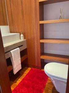 uma casa de banho com um WC branco e um tapete vermelho em Expo Luxury apartment em Lisboa