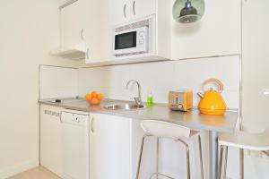 una cucina bianca con lavandino e forno a microonde di Blume Cruz Suites a Madrid