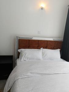 a large bed with white sheets and a wooden headboard at legatus cozy studios 1a in Ongata Rongai 