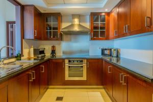 une cuisine avec des armoires en bois et un four à plaques de cuisson dans l'établissement Bellavista - High Floor - 1BR 29 Boulevard - Burj Khalifa & Fountain View, à Dubaï