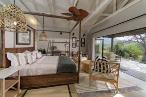 鄧迪的住宿－Valley Lodge - Babanango Game Reserve，卧室配有一张床和一张桌子及椅子