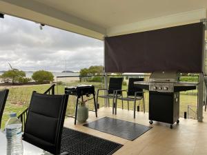 a patio with a grill and a table with chairs at ABSOLUTE BEACHFRONT Port Stephens - Pindimar Beach House in Pindimar +49 photos