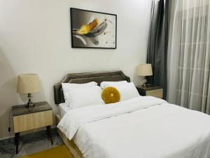 1 dormitorio con 1 cama y 2 mesitas de noche con lámparas en White villa apartment en Kigali