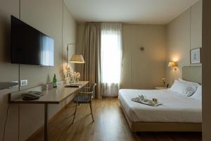 チニゼッロ・バルサモにあるコスモ ホテル パレスの大きなベッドとデスクが備わるホテルルームです。