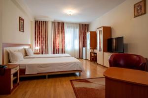 a hotel room with a bed and a flat screen tv at Primavera 1 Hotel in Pazardzhik