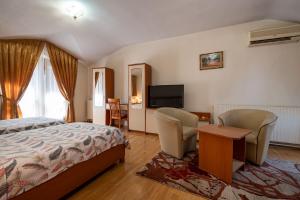 a bedroom with a bed and two chairs and a television at Primavera 1 Hotel in Pazardzhik