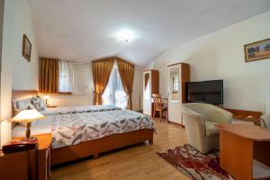 1 dormitorio con 1 cama, TV y silla en Primavera 1 Hotel, en Pazardzhik