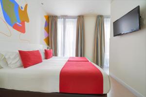 1 dormitorio con 1 cama con almohadas rojas y TV de pantalla plana en Blume Cruz Suites, en Madrid