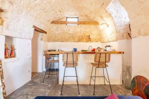 uma cozinha com bancos de bar e uma parede de pedra em Lamia Paradiso with Pool - Happy Rentals em Ceglie Messapica