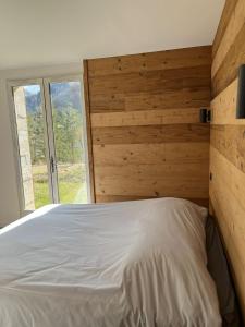 um quarto com uma cama branca e uma parede de madeira em Le Chalet des Sommets em Arvieux