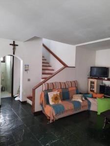 a living room with a couch and a staircase at Praia Itacoatiara Casa Jardim in Niterói