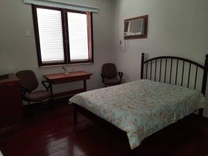 a bedroom with a bed and a desk and a window at Praia Itacoatiara Casa Jardim in Niterói