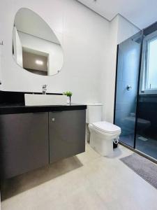 a bathroom with a sink and a toilet and a mirror at Apartamento em Bento Gonçalves in Bento Gonçalves