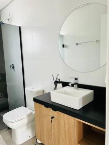 a bathroom with a sink and a toilet and a mirror at Apartamento em Bento Gonçalves in Bento Gonçalves