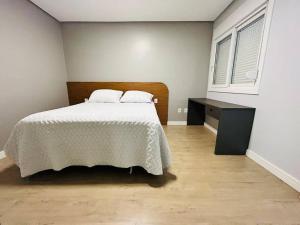 a bedroom with a white bed with a wooden headboard at Apartamento em Bento Gonçalves in Bento Gonçalves