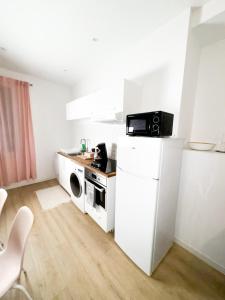 uma pequena cozinha com fogão e micro-ondas em Bégonias Appartement T3 Avenue de Lodève em Montpellier