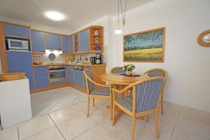 een keuken met blauwe kasten en een tafel en stoelen bij Dünenhaus Christa - Wohnung 10 - strandnah in Bansin