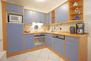 een keuken met blauwe apparatuur en houten kasten bij Dünenhaus Christa - Wohnung 10 - strandnah in Bansin