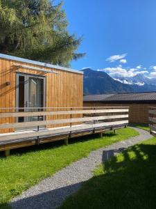 un edificio de madera con bancos en el césped en Unique Tiny Eco Lodges with gorgeous views to Jungfrau Massiv, en Interlaken