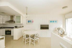 a white kitchen with a table and chairs at 106casa bocana inmo apartaments roses in Roses