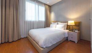 Un dormitorio con una gran cama blanca y una ventana en Friemily Pool Villa & Hotel en Geoje 