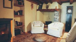 sala de estar con 2 sillas blancas y chimenea en La Taverna dei Due Gufi, en Saint-Rhémy-en-Bosses