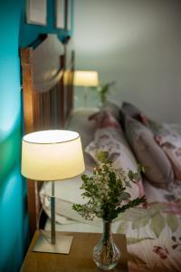 una mesa con una lámpara y un jarrón con flores en Hotel Casa Palacio Uclés en Uclés