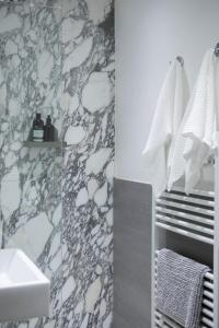 uma casa de banho com um lavatório branco e uma parede em mármore em The Luxury Inn em Londres