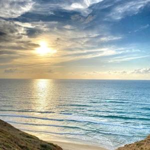 uma vista para o oceano com o sol no céu em the pool on the sea em Netanya