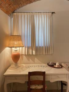 einen Schreibtisch mit einer Lampe und einen Tisch mit einem Fenster in der Unterkunft Grotto Flora B&B Chambres de charme in Bigogno