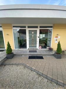 una porta d'ingresso di un edificio con due alberi da vaso di Atrium Garni a Herzogenaurach