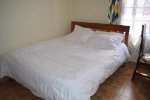 1 dormitorio con 1 cama con sábanas y almohadas blancas en Modern Ruiru double deluxe, Thika Road en Ruiru