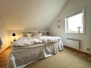 - un lit blanc dans une chambre avec fenêtre dans l'établissement Modern and cozy cottage near beautiful Fjallbacka, à Fjällbacka