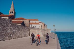 two people riding bikes on a pier next to the water at Valamar Diamant Hotel in Poreč