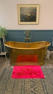 baño con bañera de madera y alfombra rosa en The Totnes Guest House. Upstairs at Zappa's, en Totnes